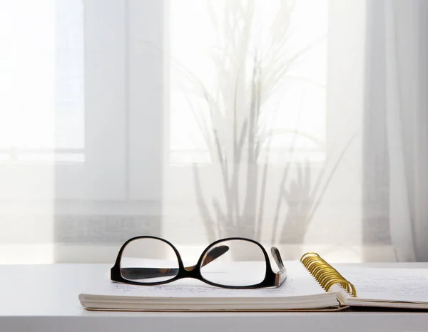 안경을 쓰고 침대에 누워 있는 탁트인 공책의 사진. — 스톡 사진