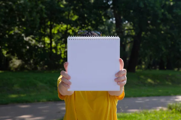 Mujer joven en camiseta amarilla sosteniendo un libro blanco delante de ella — Foto de Stock