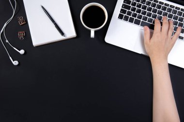 Laptop, kulaklık, kalem ve kahve dolu siyah ofis masası.. 