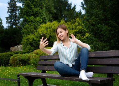 Beyaz bir kadın telefon ekranına bakar ve elini sallar.