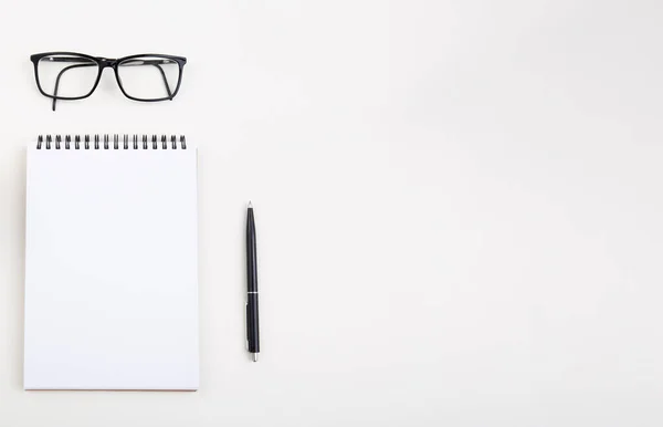 White notepad with black pen and glasses on light table, — Stock Photo, Image