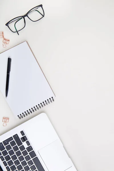 Dizüstü bilgisayarı, beyaz defter modeli ve gözlüklü hafif ofis masası. 