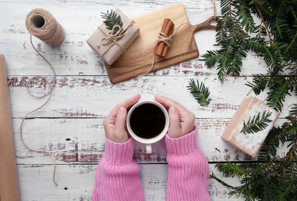 girl puts cup of coffee on the table with gifts