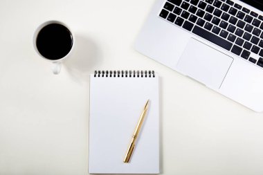 Dizüstü bilgisayarlı hafif ofis masası, beyaz defter modeli ve kahve fincanı.. 