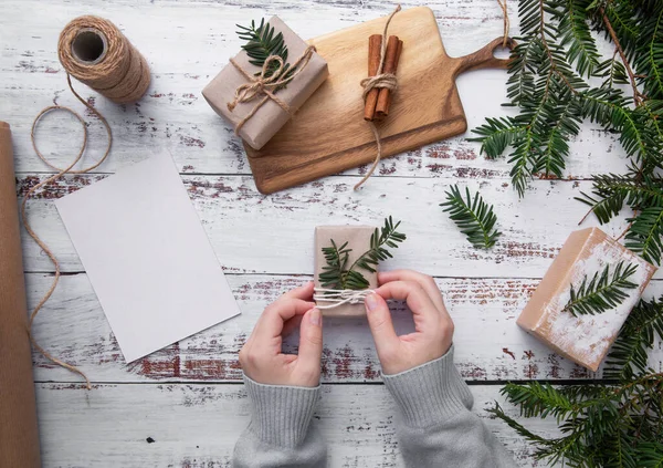 Eller beyaz sicimle Noel süslemesi yapar ve beyaz arka planda köknar 
