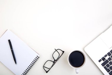 Dizüstü bilgisayarlı hafif ofis masası, beyaz defter modeli, bardaklar ve kahve fincanı. 
