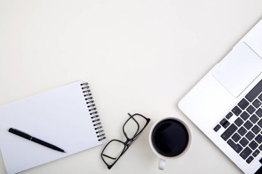 Dizüstü bilgisayarlı hafif ofis masası, beyaz defter modeli, bardaklar ve kahve fincanı. 
