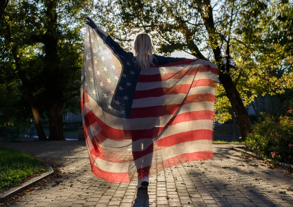 Pige holder et stof med et tryk af det amerikanske flag - Stock-foto