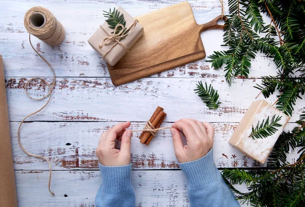 Las manos de un niño haciendo decoración de Navidad en una mesa con ramas de abeto — Foto de Stock