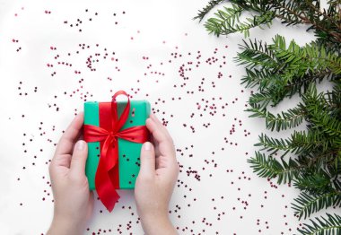 Noel hediyesini kırmızı kurdeleyle tutan eller 