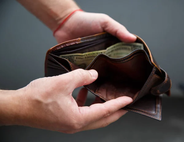 Erkek eli açık bir cüzdan tutar ve içinde sadece bir dolar vardır.