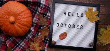 Tahtada balkabağı, sarı yapraklar ve eski ahşap bir masada kırmızı gömlek var.