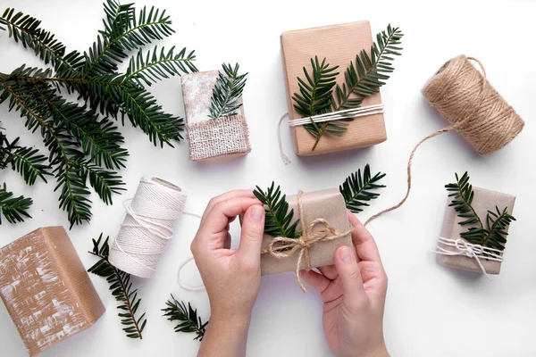 hands wrapping gifts for christmas holidays. next to threads and boxes