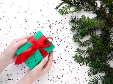 Noel hediyesini kırmızı kurdeleyle tutan eller 