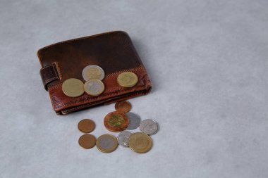 Masanın üzerinde eski bir cüzdan var ve üzerinde küçük metal paralar var.