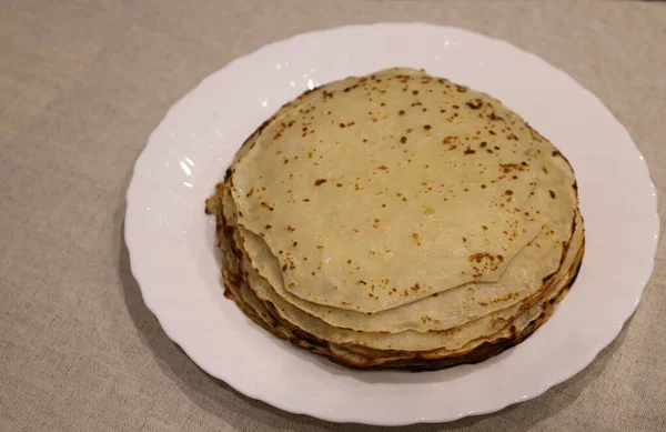 Plato blanco sobre mantel de lino con panqueques frescos según receta rusa —  Fotos de Stock