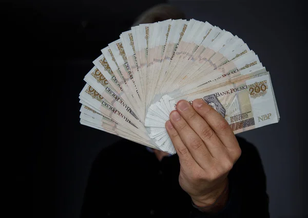 man hand holds a fan of 200 PLN banknotes in front of him