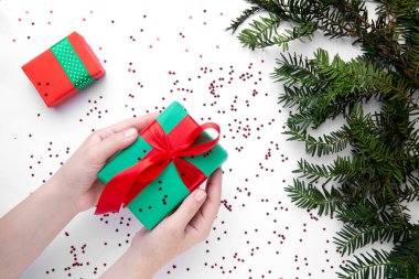 Noel hediyesini kırmızı kurdeleyle tutan eller 