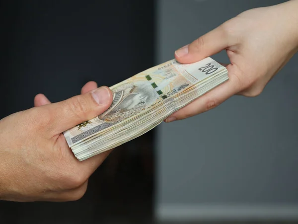 Erkek eli, kadın ellerine bir tomar para veriyor.