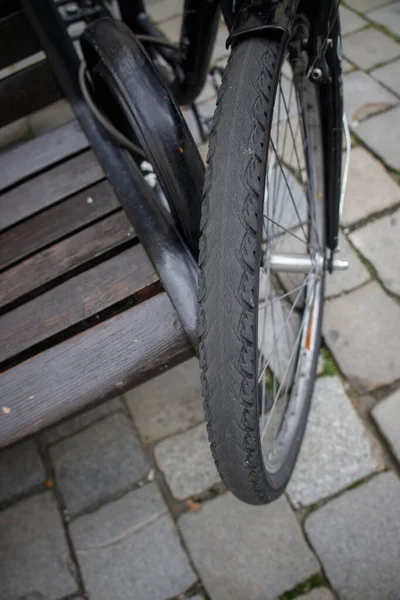 bicycle tire with frayed tread on the front wheel of a bicycle parked by bench