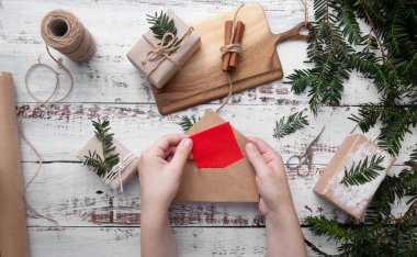 Kızlar ellerinde beyaz arkaplanda kırmızı kağıt olan bir zarf tutuyor. 