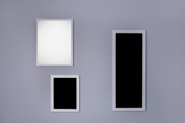 Boş gri duvarda üç çerçeveli poster modeli 