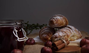 Tarçınlı taze kruvasanlar, çilek reçeli ve elmalar masanın üzerinde.. 