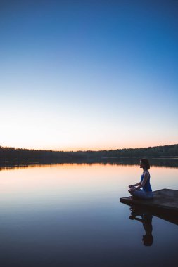  Yoga yapan kadın dışarıda fitness yaşam tarzı için hayati önem taşıyor ve meditasyon yapıyor. Gölde gün doğumu. Doğa geçmişi. Sağlıklı ve Yoga Konsepti. Huzurlu bir yaşam tarzı. Boşluğu kopyala