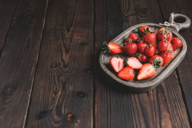 Koyu, ahşap bir arka planda, Woofen kesme tahtasındaki taze kırmızı olgun çilekler. Boşluğu kopyala