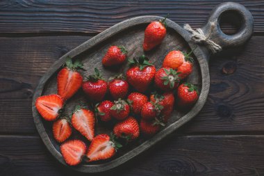Koyu, ahşap bir arka planda, Woofen kesme tahtasındaki taze kırmızı olgun çilekler. en üstteki görünüm