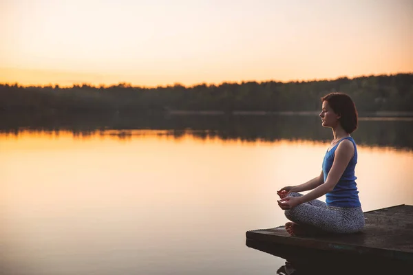 Mulher exercendo ioga pose vital e meditação para o estilo de vida fitness fora. nascer do sol no lago. fundo da natureza. Conceito saudável e Yoga. Estilo de vida pacífico. espaço de cópia — Fotografia de Stock