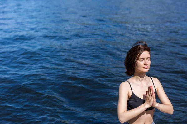 Mulher praticando ioga com namaste nas costas. estilo de vida fitness no fundo da água ao ar livre. Dia ensolarado em pinhal. espaço de cópia — Fotografia de Stock