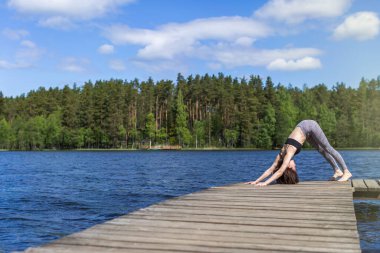 Yoga ve egzersiz yapan bir kadın. Doğa arka planında fitness yaşam tarzı. Gölde güneşli bir gün