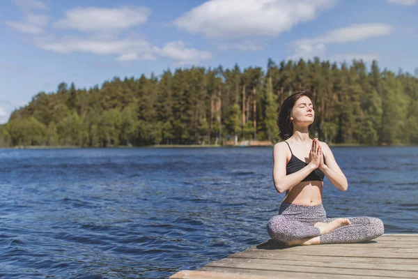 Mulher praticando ioga com namaste nas costas. estilo de vida fitness no fundo da água ao ar livre. Dia ensolarado em pinhal. espaço de cópia — Fotografia de Stock