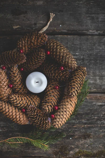 Christmas decoration, wreath with spruce cones, berryes and candle. top view