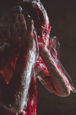 Çığlık atan insan yüzü plastik gerilme zarından geçerek korku arka planı olarak kırmızı renge boyanmış.