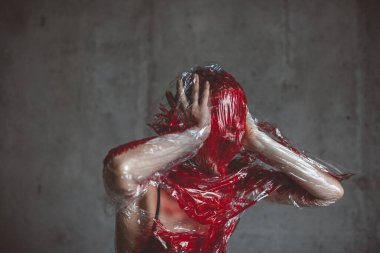 Plastik gerilme zarına bastıran insan yüzü kırmızıya boyanmış. Boşluğu kopyala