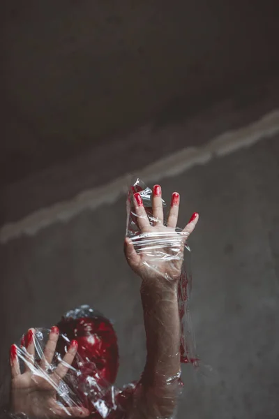 Plastik gerilme zarında insan eli kırmızıya boyanmış. Boşluğu kopyala
