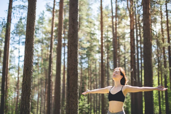 Mulher feliz com as mãos abertas contra árvores altas e fundo floresta de pinheiros. Pessoa desfrutar da natureza após a prática de ioga. Conceito de liberdade e imaginação — Fotografia de Stock