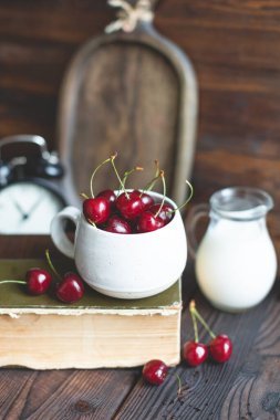 taze böğürtlen organik kırmızı olgun tatlı kiraz beyaz seramik bardakta ve ahşap rusik arka planda süt