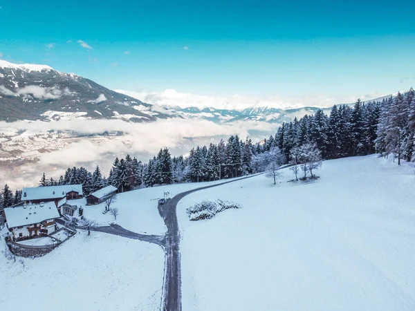 Uitzicht vanuit de lucht op besneeuwde bewolkte bergen, bos met een weg, klein chalethuisje. Van boven gevangen met een drone. Dolomieten Alpen- Italië — Stockfoto