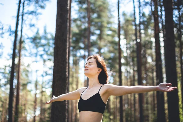 Happy woman with open hands against high trees and pine forest background. Person enjoy nature after yoga practicing. Freedom and imagination concept