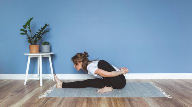 Kadın evde yoga yapıyor, mavi duvar arkaplanı, kopyalama alanı