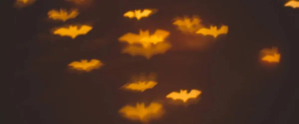 Defocused bokeh gold lights in shape of bats for halloween background - holidays, decoration and party concept. banner — Stock Photo, Image