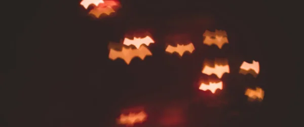 Rozproszone bokeh złote światła w kształcie nietoperzy na halloween tle - wakacje, dekoracja i koncepcja partii. sztandar — Zdjęcie stockowe
