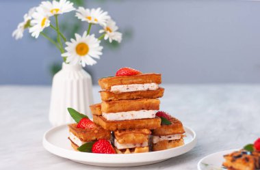 Çikolata, krem şanti, nane şekeri ve taze doğranmış çilekli Belçika waffle 'ı. Ev yapımı lezzetli bir tatlı ve papatya arkaplanı.