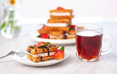 Çikolata, krem şanti, nane şekeri ve taze doğranmış çilekli Belçika waffle 'ı ile kaplanmış bir fincan çay. Ev yemeği lezzetli tatlı