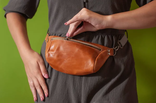 Waist bag made from natural leather close-up view on the unrecognizable woman on the green background