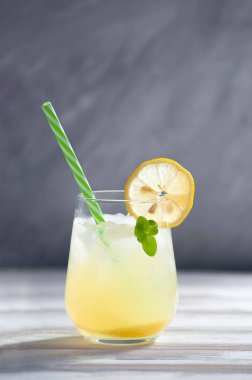 Dilimlenmiş limon süslemesi, nane yaprağı ve yeşil pipetle buzlu limonata tazeleniyor.