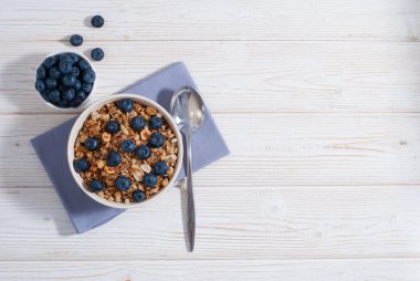 Mısır gevreği ve yaban mersinli kahvaltı beyaz masa düz kopya alanında. Sağlıklı sabah yemeği.